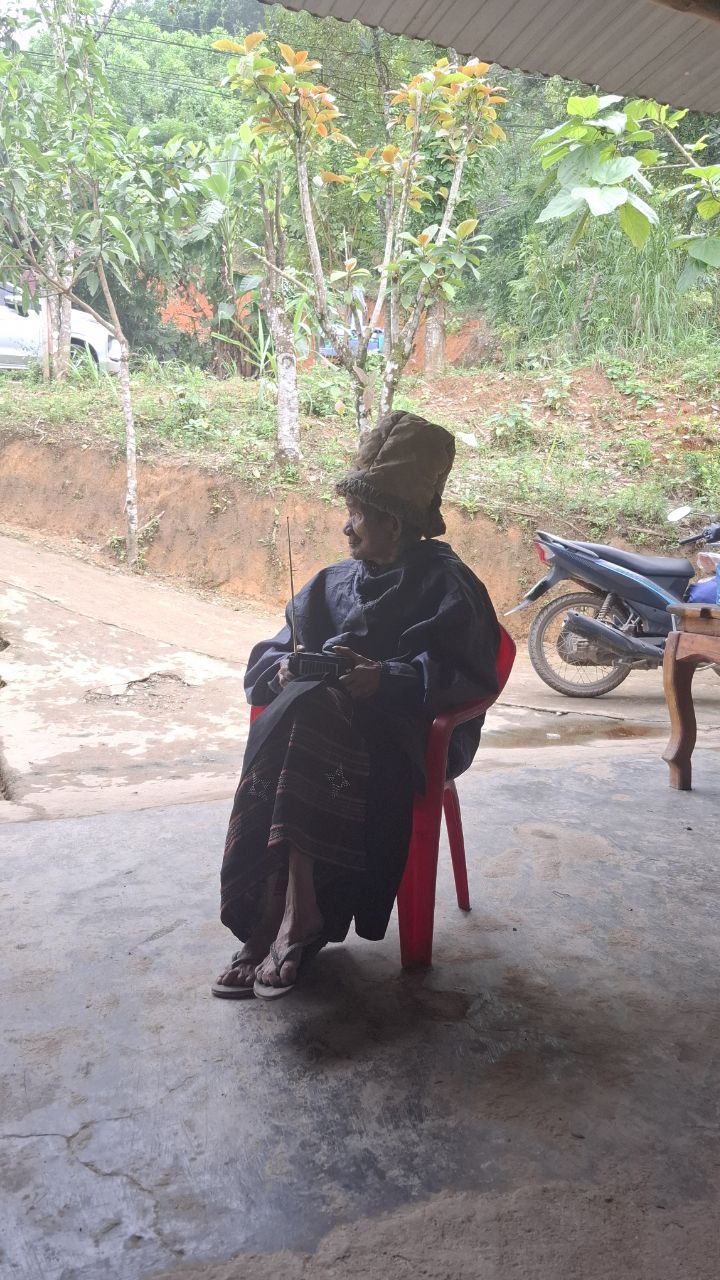 Hearing God's Word — a village elder listens quietly at home.