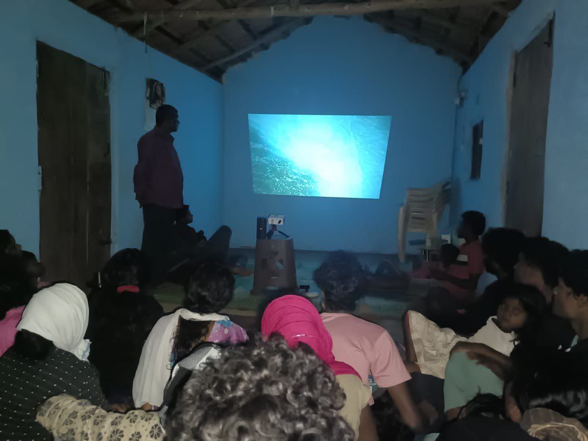 Teaching one another — a household gathers around the Jesus Film.
