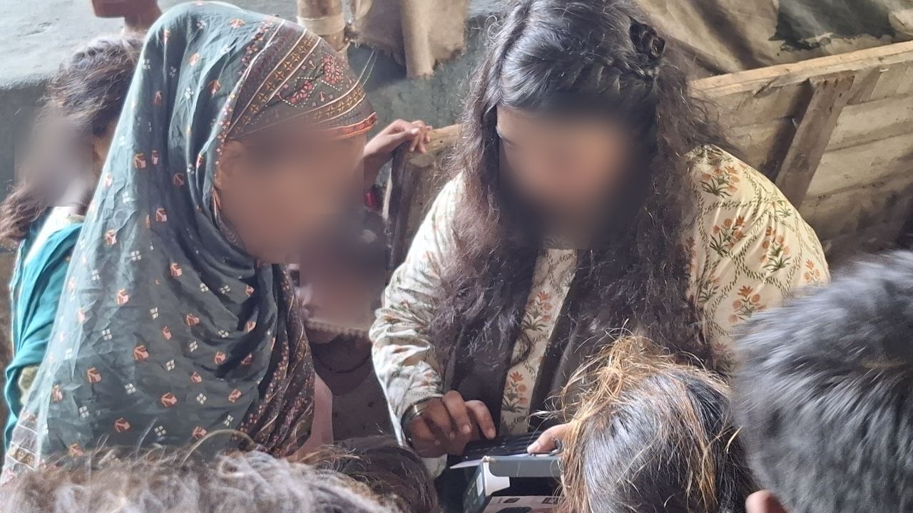 Sharing — one woman shows another how the player works, Pakistan. Faces blurred to protect privacy.